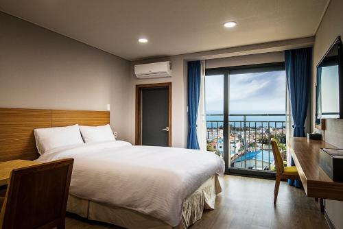 a hotel room with a bed and a balcony at W Ocean Pension in Seogwipo