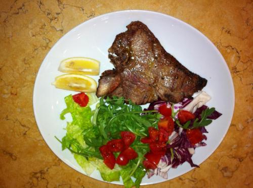 a plate of food with meat and salad on a table at Hotel Girasole in Civitanova Marche
