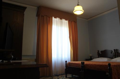 a bedroom with a bed and a window with an orange curtain at Hotel Girasole in Civitanova Marche