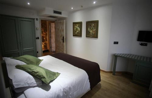 a bedroom with a bed with white sheets and green pillows at Boutique Hotel Castilla in Soria