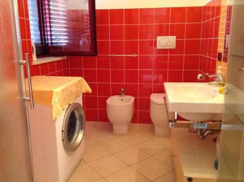 La salle de bains est pourvue de carrelage rouge, de toilettes et d'un lavabo. dans l'établissement Lido delle Farfalle, à Casalbordino