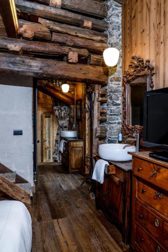 a bathroom with a sink and a tv in a cabin at Hotel Du Grand Paradis - 1899 Auberge Boutique in Cogne