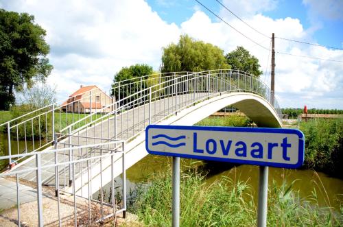 a bridge over a river with a sign in front of it at Vakantiewoning De Machuut in Lo-Reninge