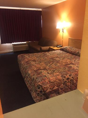 a hotel room with a bed and a chair at Camelot Inn in Amarillo