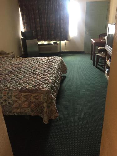 una camera d'albergo con letto e scrivania di Camelot Inn ad Amarillo