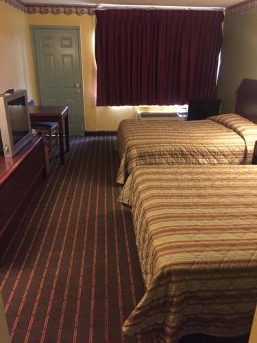 a hotel room with two beds and a flat screen tv at Camelot Inn in Amarillo