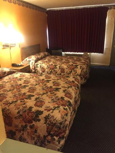 a hotel room with two beds with a floral bedspread at Camelot Inn in Amarillo