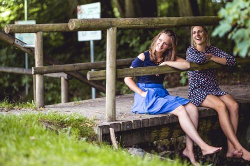 two girls are sitting on a wooden bridge at Hotel Alpenrose in Bad Wörishofen