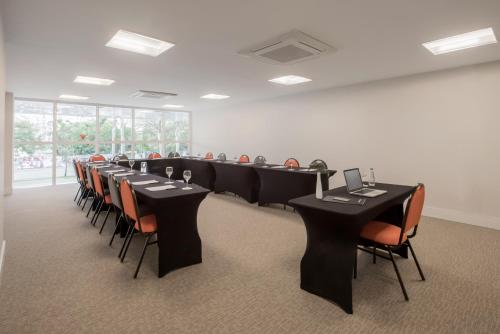 a conference room with black tables and orange chairs at Intercity Porto Alegre Cidade Baixa in Porto Alegre