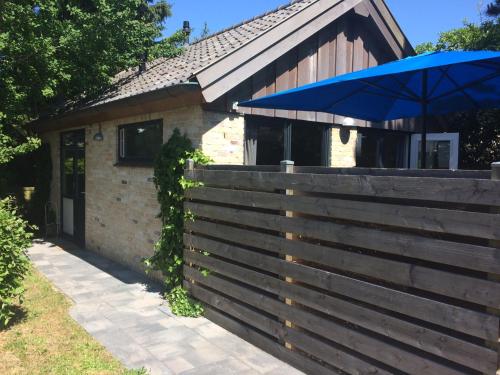 a house with a fence and a blue umbrella at Texelduinen59 in De Koog