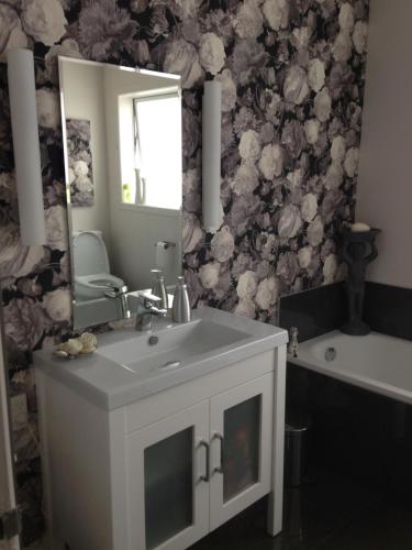 a bathroom with a sink and a mirror and a tub at Beach Side B & B in Auckland