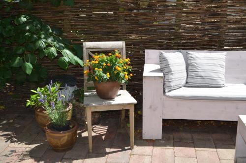 a chair and a table with flowers on a patio at Hotel De Waag in Bergen