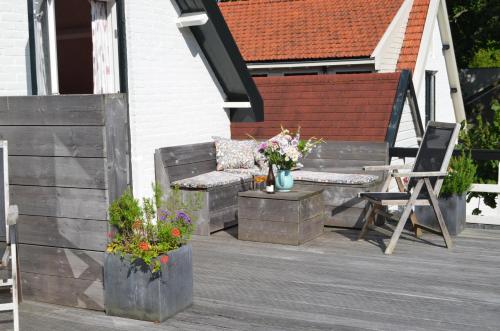 a patio with a bench and a chair and flowers at Hotel De Waag in Bergen