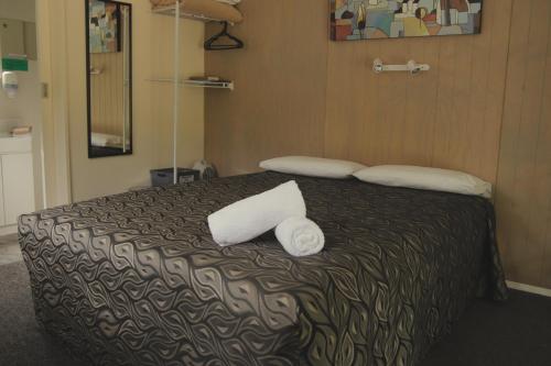 a bedroom with a bed with two towels on it at Geraldine TOP 10 Holiday Park in Geraldine