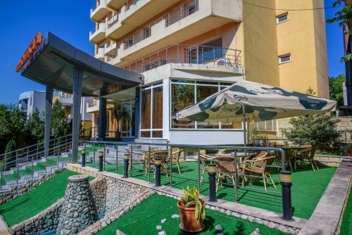 a patio with tables and chairs and an umbrella at Hotel Scala in Constanţa