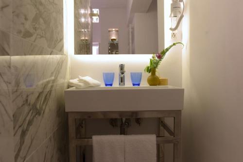 a bathroom sink with two blue glasses and a mirror at Achillion Liston Suites in Corfu Town