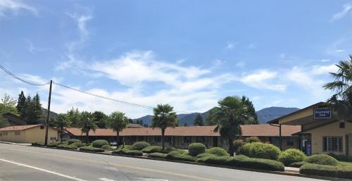 an empty street with palm trees and a building at Bestway Inn in Grants Pass