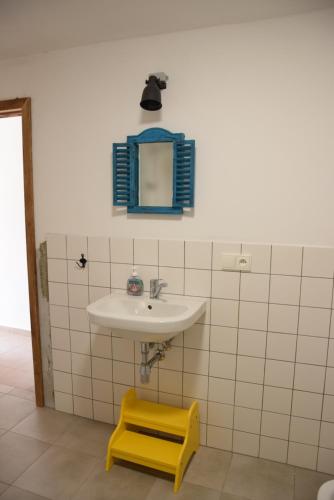 a bathroom with a sink and a mirror and a yellow stool at Apartmány Kojákovice - Třeboň in Jílovice