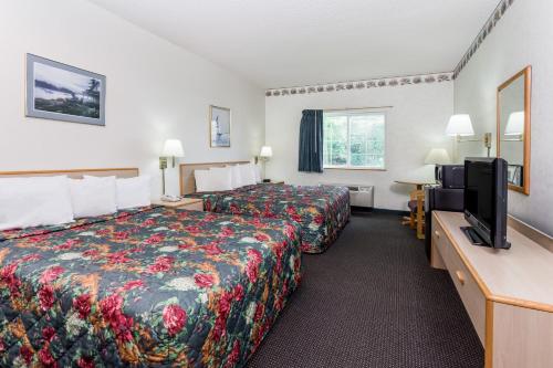 a hotel room with two beds and a flat screen tv at AmericInn by Wyndham Eagle River Downtown in Eagle River
