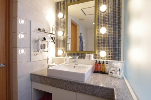 een badkamer met een witte wastafel en een spiegel bij BlueHotel sju(:)pri:m (Adult Only) in Sapporo