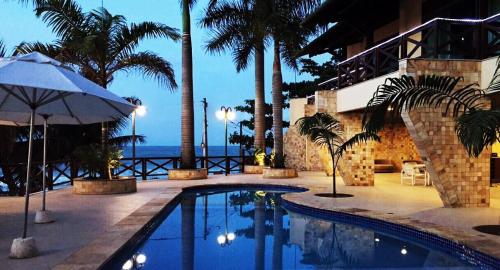 a swimming pool in a resort with palm trees and the ocean at Pipa Mar Hotel in Pipa