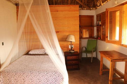 a bedroom with a canopy bed and a desk at Cafe Maya - Casa Acalli in Zipolite