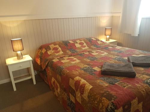 ein Schlafzimmer mit einem Bett und zwei Tischen mit Lampen in der Unterkunft BIG4 Hay in Hay