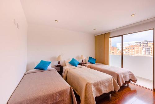 2 camas en una habitación con ventana grande en Apartamentos Aeropuerto Corferias, en Bogotá