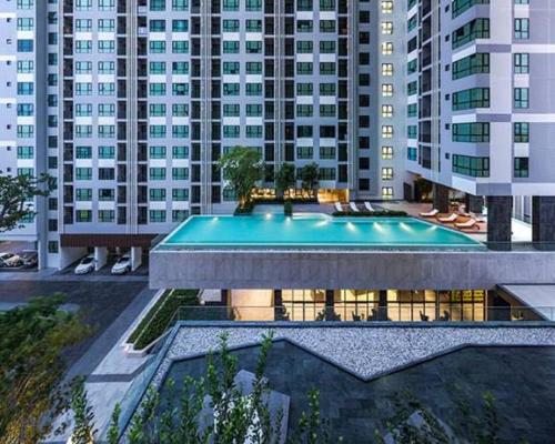 a swimming pool in front of a building with tall buildings at The Base Central Pattaya in Pattaya Central