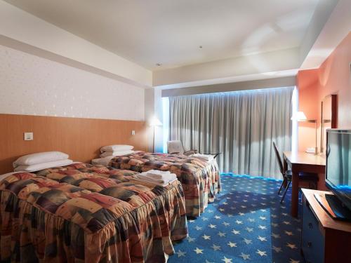 a hotel room with two beds and a flat screen tv at Hotel Seagull Tenpozan Osaka in Osaka