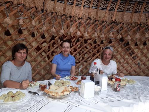 three women sitting at a table with food at Yurt camp Meiman Ordo in Bokonbayevo