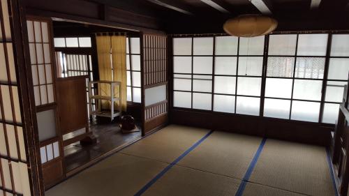 ein leeres Zimmer mit Fenstern und einer Tür in der Unterkunft Minshuku Suhara in Okuwa