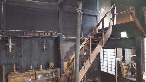 eine hölzerne Wendeltreppe in einem Zimmer mit Fenster in der Unterkunft Minshuku Suhara in Okuwa
