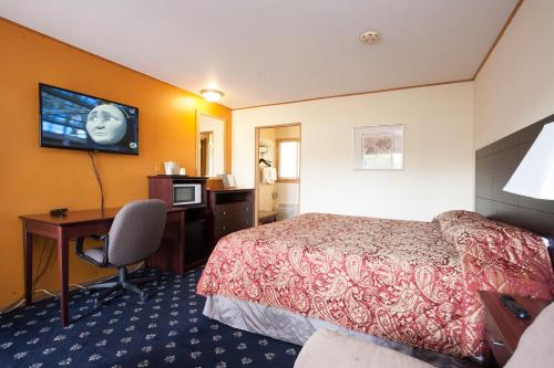 a hotel room with a bed and a desk and a television at Park Motel in Marshfield