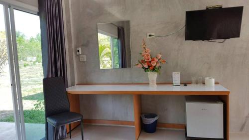 a desk with a mirror and a vase of flowers on it at Phurang Hill Resort in Kanchanaburi