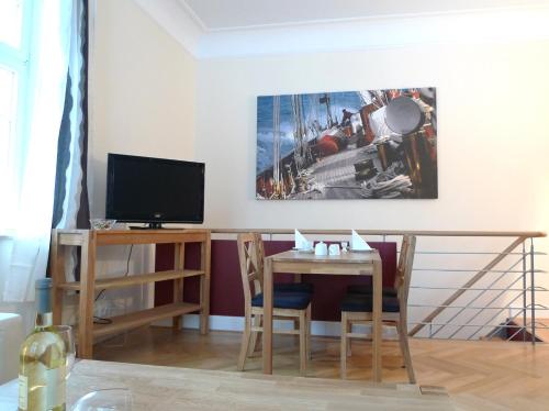 a living room with a table and a television at Villa Andante Apartmenthotel in Kassel