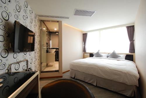 台北的住宿－欣欣旅店，一间卧室配有一张床、一台电视和一间浴室。