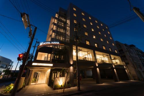 a tall building with a sign on it at night at RJ Hotel Naha in Naha
