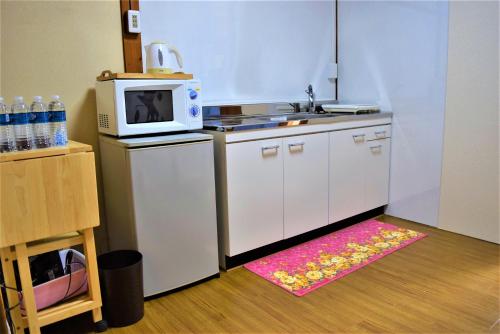 eine kleine Küche mit einer Mikrowelle und einem Teppich in der Unterkunft Guest House WASSO in Kyoto