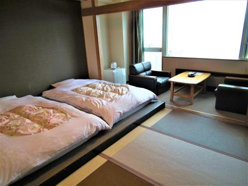 een slaapkamer met een bed, een stoel en een tafel bij Granvillage Toya Daiwa Ryokan Annex in Lake Toya