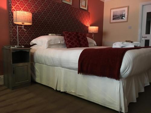 a bedroom with a large bed with a red wall at Ellan Vannin Hotel in Douglas