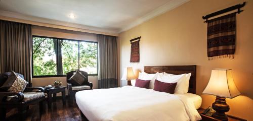 a hotel room with a bed and a chair and a window at Prince Angkor Hotel & Spa in Siem Reap