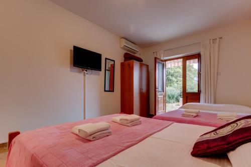 a bedroom with two beds and a tv on the wall at Studio Apartments Petkovic in Tivat