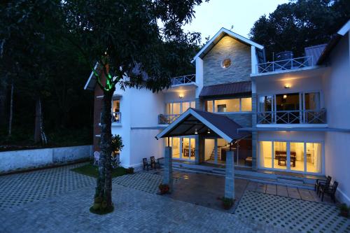 a large white house with a black awning at Crayons Guest House Munnar in Munnar