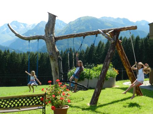 a family playing on a swing set in a yard at Apartment Bauernhof Thurnummerstall in Hollersbach im Pinzgau