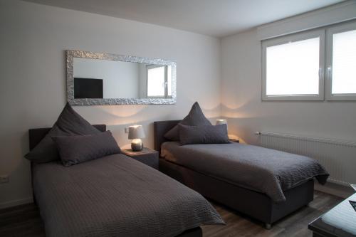 ゾーリンゲンにあるDie Hotelalternativeのベッドルーム1室(ベッド2台、壁掛け鏡付)