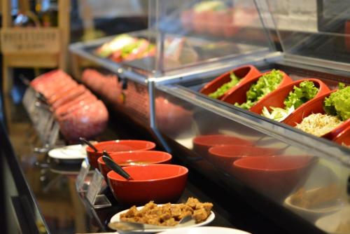 a buffet line with dishes of food and vegetables at Luminor Hotel Jemursari By WH with The Best Breakfast in Town and Located Near Surabaya Industrial Estate Rungkut SIER in Surabaya