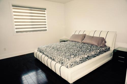 a bed in a white room with a window at Luxury Two Story Villa Unit C in Laval
