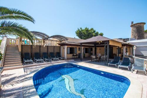 a swimming pool with chairs and a house at Villa Marina in Playa de Palma in Palma de Mallorca