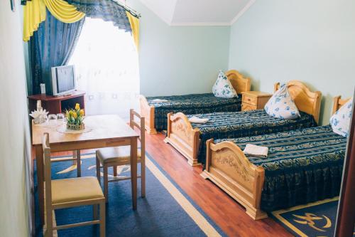 um quarto com duas camas e uma mesa e uma mesa e cadeiras em Berizka em Perechin